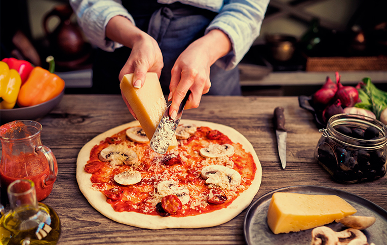 Chef poniendo queso en pizza